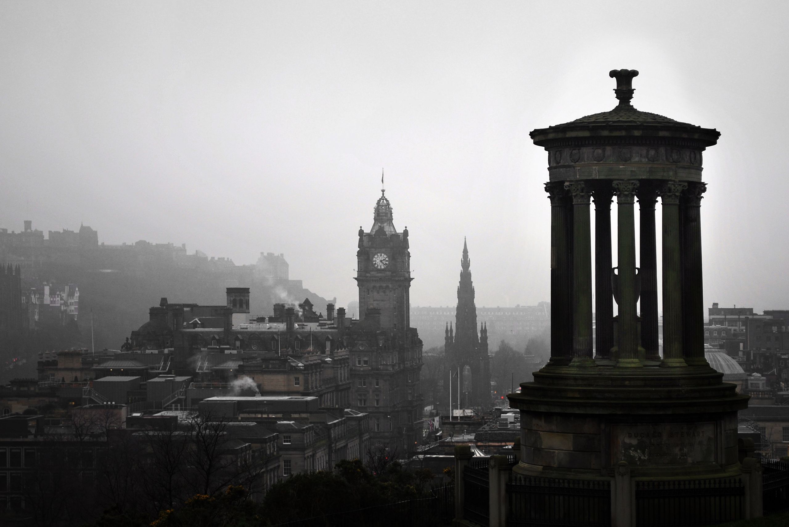 A scenic view of Edinburgh's iconic Calton Hill under grey skies, featuring historic monuments.