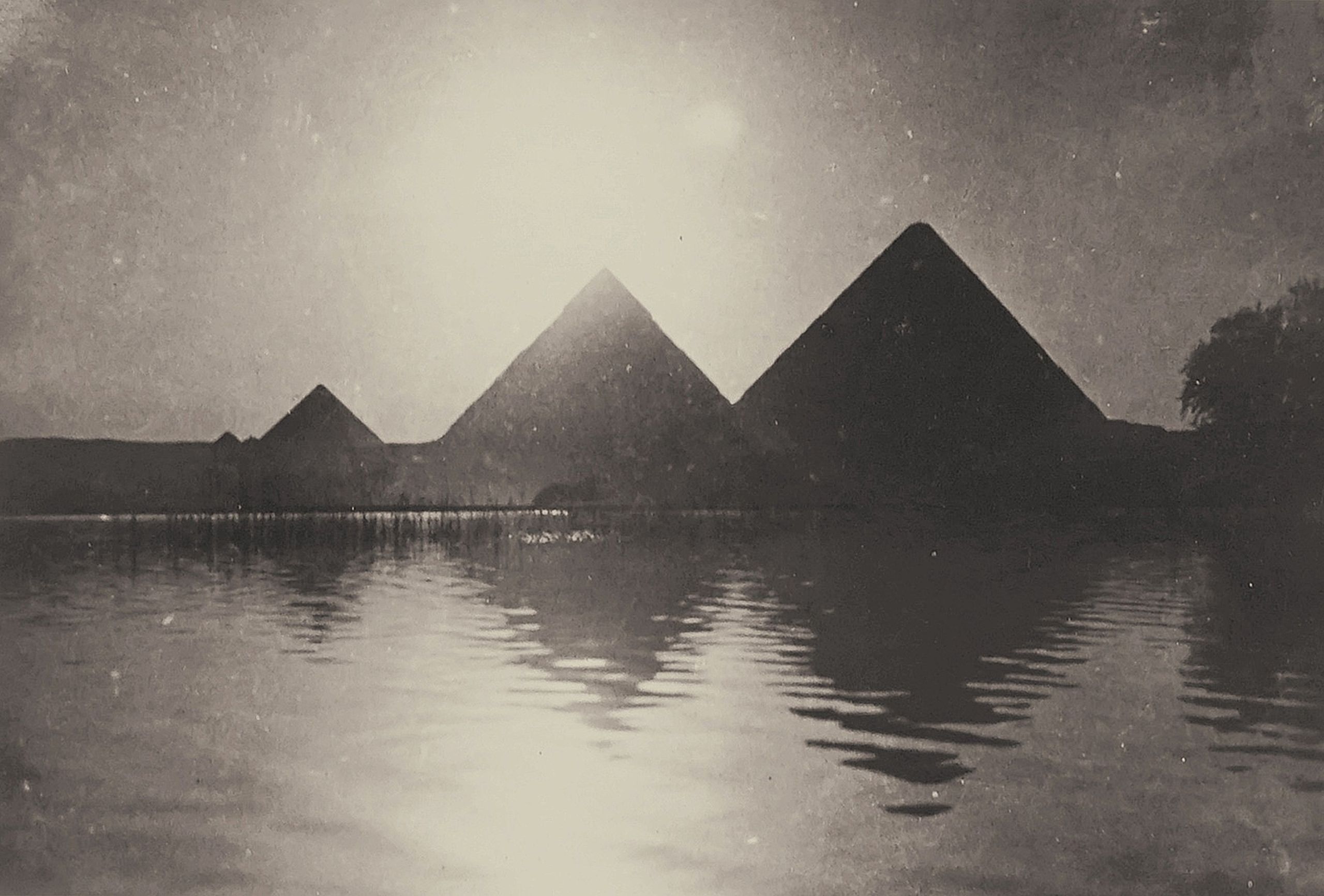 Classic vintage monochrome photo of Egyptian pyramids with water reflection.